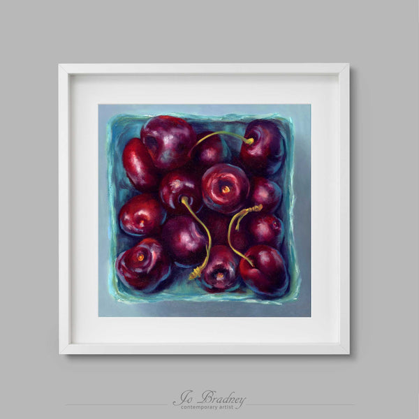 A box of fresh red summer cherries ina turquoise blue farmers market box. This archival art print of my fruit still life oil painting is shown in simple white square picture frame.