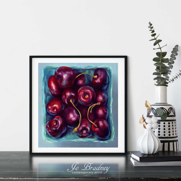 A cherry oil painting print framed in a simple, elegant black picture frame on a dining room or living room wall. There are flowers in vase, set on a wood buffet table. The smallest square print on paper is 4 inches, the largest is 12 inches.
