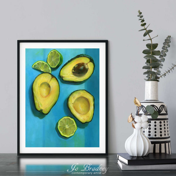 An avocdo and lime oil painting print framed in a simple, elegant black picture frame on a dining room or living room wall. There are flowers in vase, set on a wood buffet table. The smallest square print on paper is 4x6 inches, the largest is 11x14 inches.