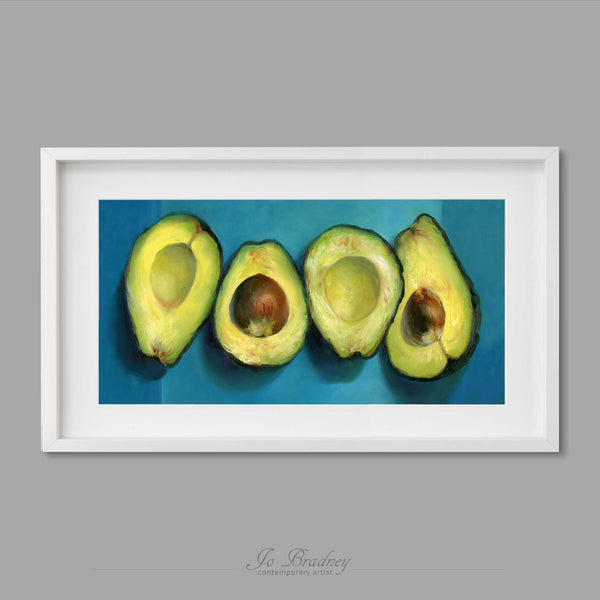 fresh green avocado halves on a bright turquoise and teal background. This long narrow art print of my vegetable still life oil painting is shown in simple white picture frame.