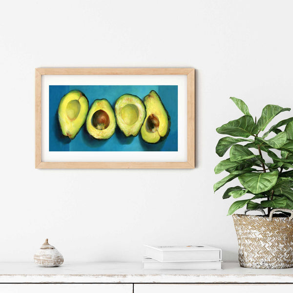 A turquoise avocado oil painting art print in a simple elegant wood frame on a dining room or living room wall. There are books and a plant in a rustic pot, on a shabby chic painted wood buffet table.