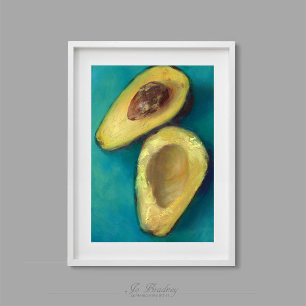 A fresh avocado cur in half and twisted apart, laying on a sea green turquoise background. This archival art print of my vegetable still life oil painting is shown in simple white picture frame.