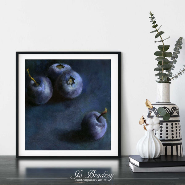 A dark blueberry oil painting art print framed in a simple, elegant black picture frame on a dining room or living room wall. There are flowers in vase, set on a wood buffet table. The smallest square print on paper is 4 inches, the largest is 12 inches.