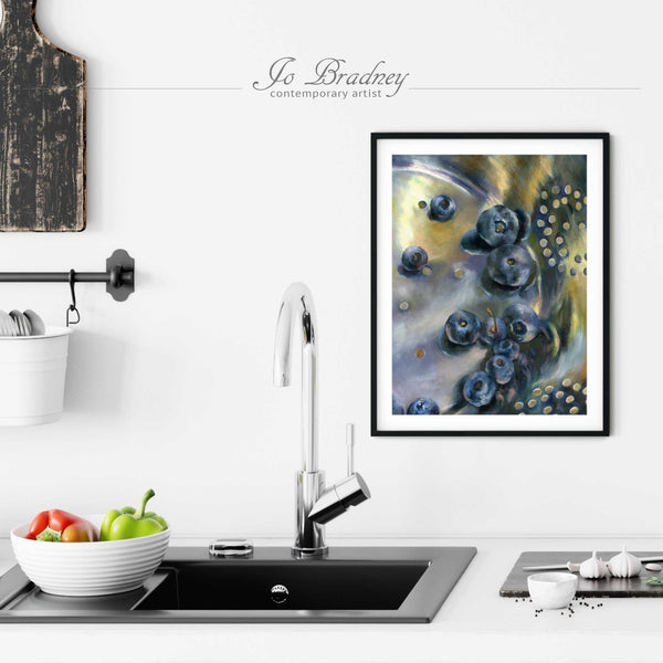 A vertical blueberry painting art print in a simple, elegant black picture frame on a kitchen wall. Placed above a modern sink, with rustic chopping boards and fresh vegetables.