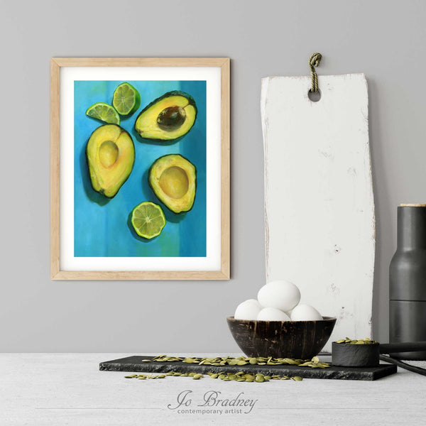 A lime and avocado art print in a simple, elegant wood picture frame on a kitchen wall. There is a bowl of eggs, and a chopping board for scale. The print is 5 eggs tall. The smallest vertical print is 4x6 inches, the largest is 11x14 inches.