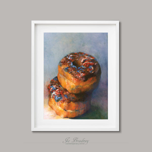 Two chocolate donuts with red, white and blue sprinkles. This archival art print of my cake still life oil painting is shown in simple white picture frame.
