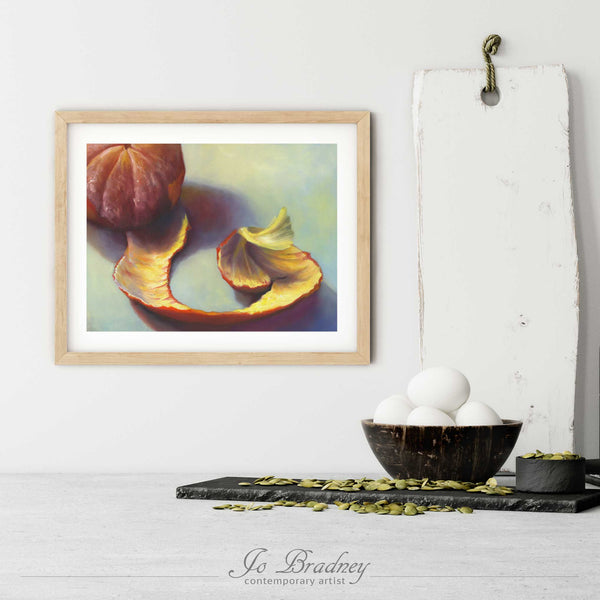 A peeled clementine art print in a simple, elegant wood picture frame on a kitchen wall. There is a bowl of eggs, and a chopping board for scale. The print is 5 eggs tall. The smallest horizontal print is 4x6 inches, the largest is 11x14 inches.