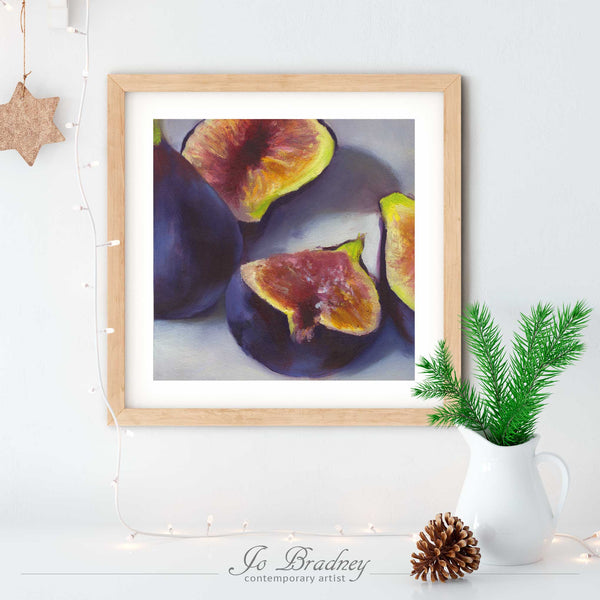 A fresh purple fig oil painting art print, in an elegant wood picture frame on a dining room or living room wall. There are Christmas lights and rustic holiday decor on a white buffet table.