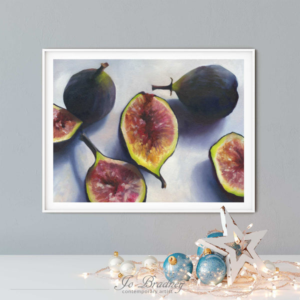A fresh fig oil painting art print, in an elegant white picture frame on a dining room or living room wall. There are Christmas ornaments on a modern white buffet table.