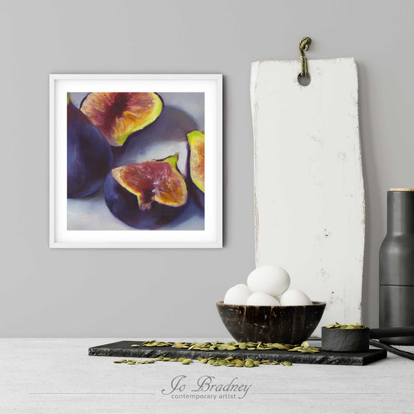 A fresh fig art print in a simple, elegant white picture frame on a modern farmhouse kitchen wall. There is a bowl of eggs, and a chopping board for scale. The print is 5 eggs tall. The smallest square print is 4 inches, the largest is 12 inches.