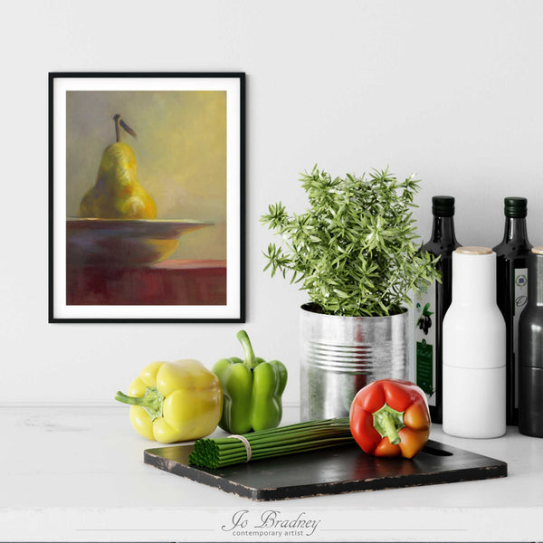 A vertical fall pear painting art print in a simple, elegant black picture frame on a kitchen wall. Placed above a modern sink, with rustic chopping boards and fresh vegetables.