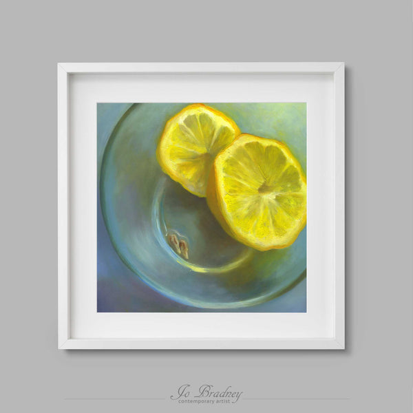 A sliced yellow lemon and two pips on a blue-green background. This archival art print of my citrus friut still life oil painting is shown in simple white picture frame.