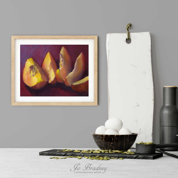 A yellow-orange and burgundy red peach art print in a simple, elegant wood picture frame on a kitchen wall. There is a bowl of eggs, and a chopping board for scale. The print is 5 eggs tall. The smallest horizontal print is 4x6 inches, the largest is 11x14 inches.