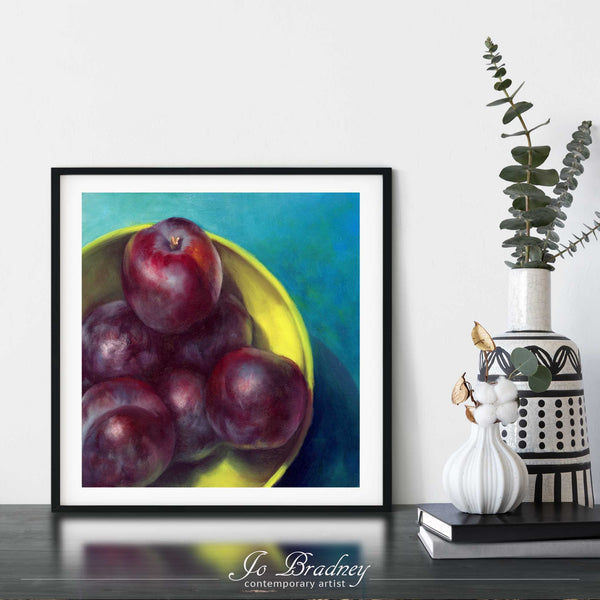 A plum oil painting fine art print framed in a simple, elegant black picture frame on a dining room or living room wall. There are flowers in vase, set on a wood buffet table. The smallest square print on paper is 4 inches, the largest is 12 inches.