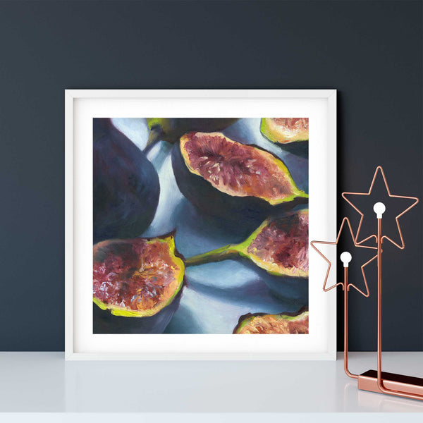 A purple and pink fig oil painting fruit art print, in an elegant white frame on a modern dining room or living room wall. There are sleek copper holiday lights on a modern white buffet table. A classy addition to your seasonal decor, lasting from Thanksgiving to Christmas.