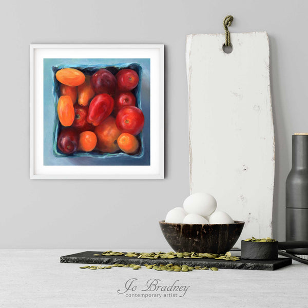 A tomato art print in a simple, elegant white picture frame on a kitchen wall. There is a bowl of eggs, and a chopping board for scale. The print is 5 eggs tall. The smallest square print is 4 inches, the largest is 12 inches.