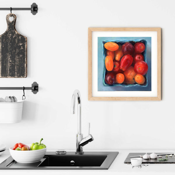 A square tomato painting art print in a simple, elegant wood picture frame on a kitchen wall. Placed above a modern sink, with rustic chopping boards and fresh vegetables.
