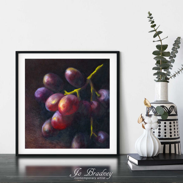 A bunch of dark grapes oil painting print framed in a simple, elegant black picture frame on a dining room or living room wall. There are flowers in vase, set on a wood buffet table. The smallest square print on paper is 4 inches, the largest is 12 inches.