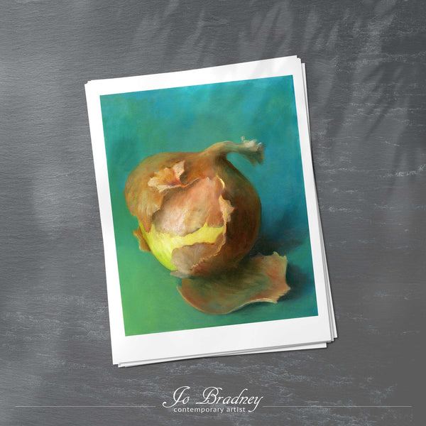 A stack of vertical art prints on archival paper on a slate kitchen counter. The prints show a yellow onion on a warm turquoise green background. This is a giclee print of my realistic oil painting still life. The original artwork is sold.