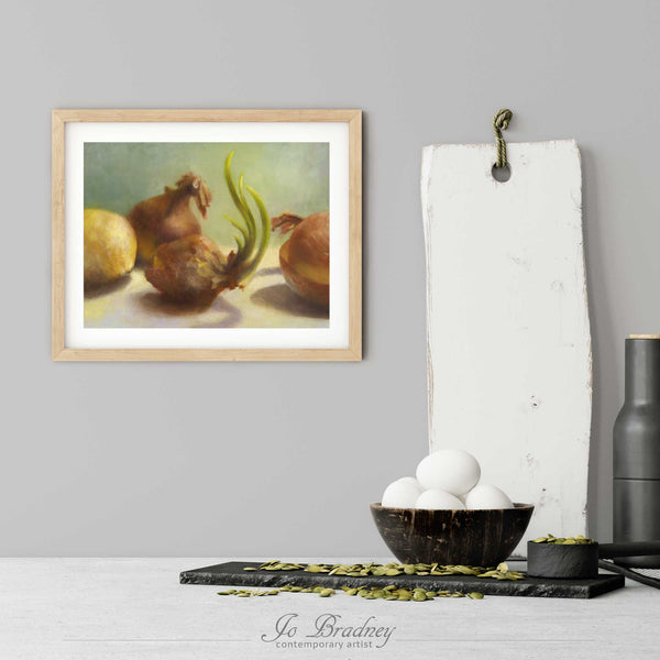 A green and yellow onion painting art print in a simple, elegant wood picture frame on a kitchen wall. There is a bowl of eggs, and a chopping board for scale. The print is 5 eggs tall. The smallest horizontal print is 4x6 inches, the largest is 11x14 inches.